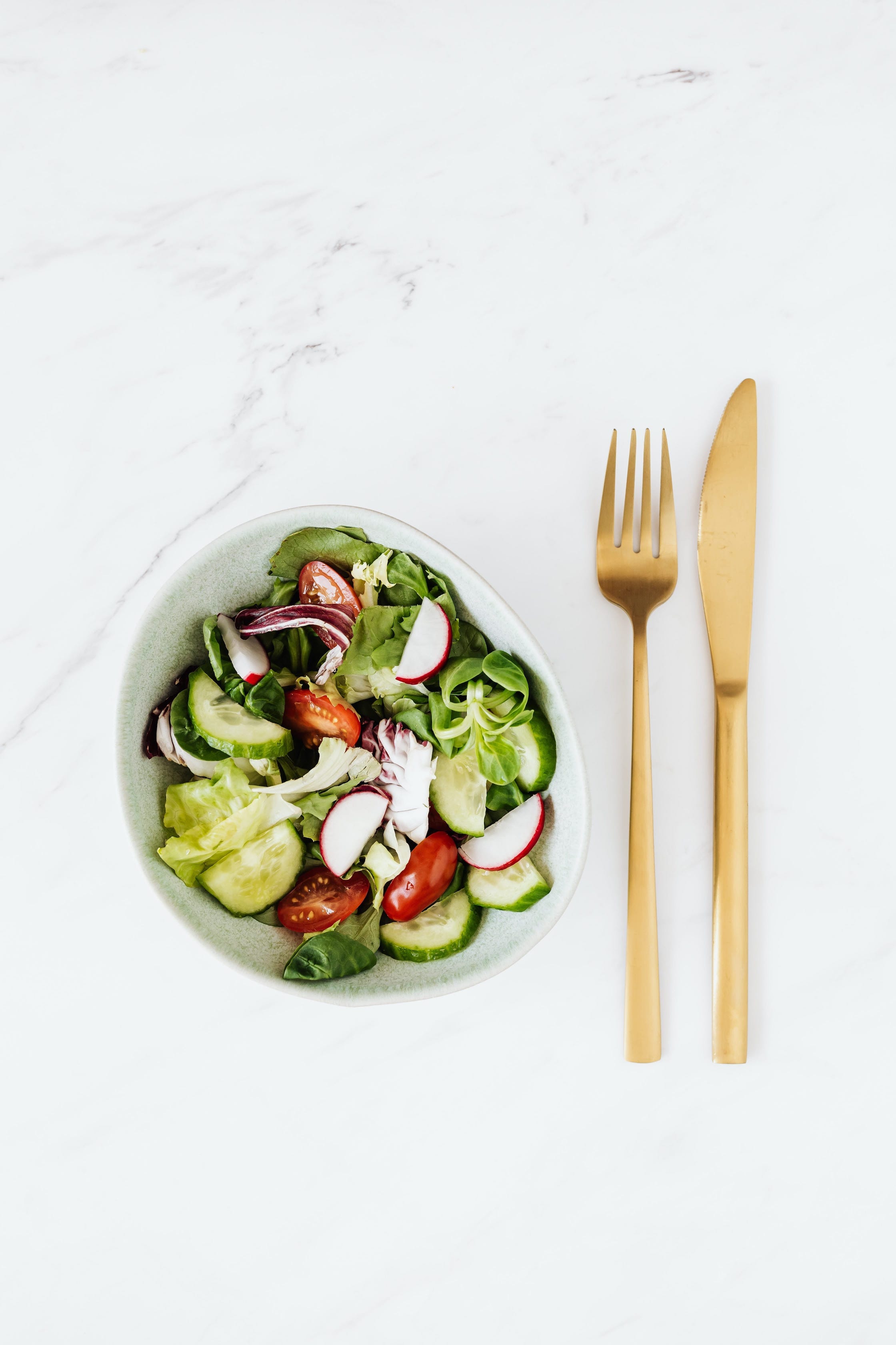 Gewürzsalat in Schüssel und Besteck